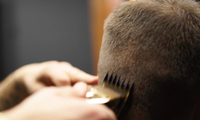 Hairdresser uses machine to trim guy's hair